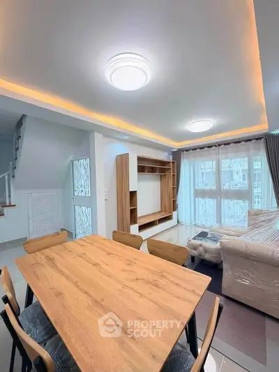Modern living room with stylish furniture and natural light, featuring a cozy dining area and elegant ceiling lights.