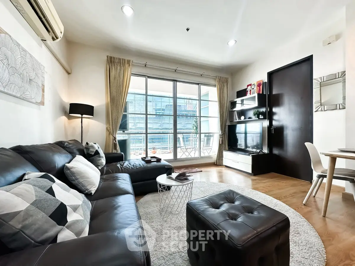 Modern living room with leather sofa, large windows, and stylish decor in a high-rise apartment.