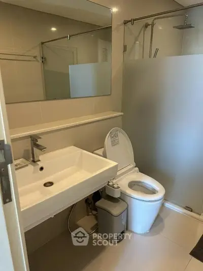 Modern bathroom with sleek fixtures and frosted glass shower in a contemporary home.