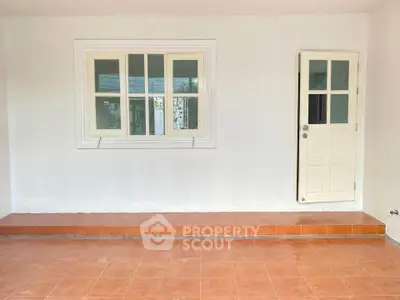 Spacious tiled patio with white door and window, perfect for outdoor relaxation.