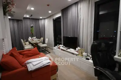 Modern living room with red sofa, dining area, and large windows in a stylish apartment.