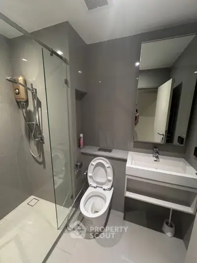 Modern bathroom with sleek design, featuring a glass shower enclosure and contemporary fixtures.
