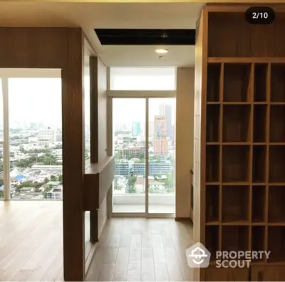 Spacious high-rise corner unit with floor-to-ceiling windows offering panoramic city views, modern wooden flooring, and built-in shelving.