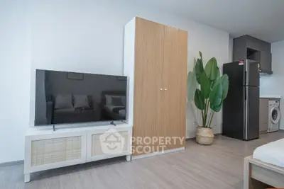 Modern living room with sleek TV, wardrobe, and stylish kitchen appliances.