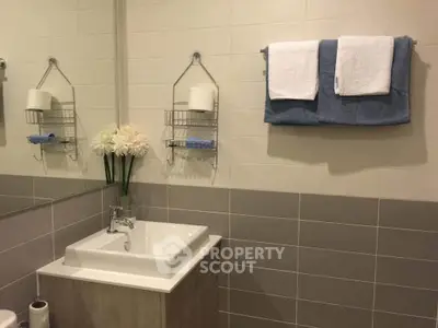 Modern bathroom with elegant sink and towel rack, featuring neutral tiles and floral decor.