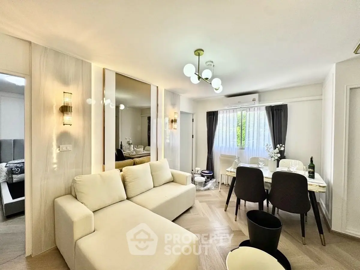 Modern living room with elegant decor and dining area, featuring a cozy white sofa and stylish lighting.