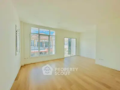Spacious and bright living room with large windows and wooden flooring