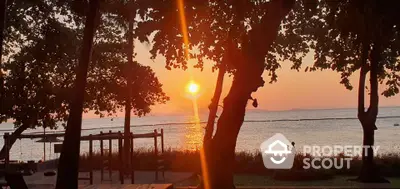 Stunning sunset view from a serene beachfront property with lush trees and tranquil atmosphere.