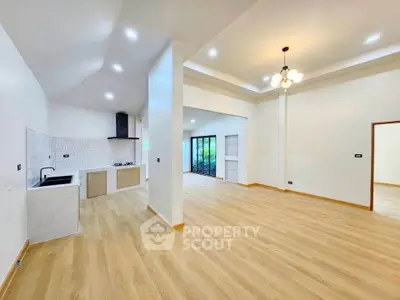 Spacious open-plan living room with modern kitchen and elegant lighting, perfect for entertaining.
