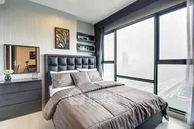 Luxurious bedroom with floor-to-ceiling windows offering stunning city views, modern decor, and elegant furnishings.