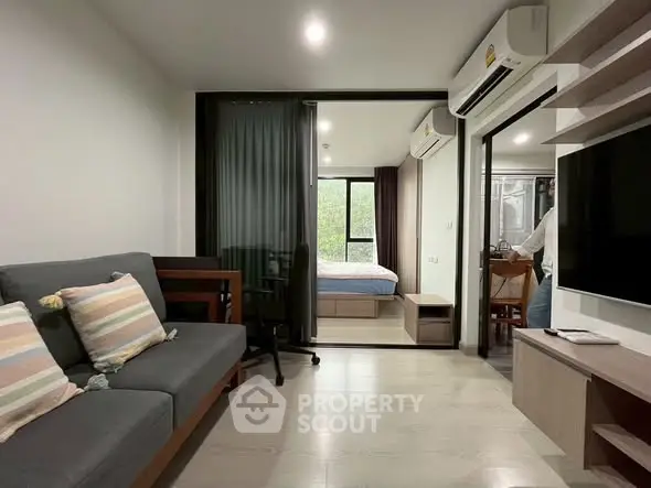 Modern apartment interior with cozy living room and bedroom view, featuring sleek furniture and natural light.