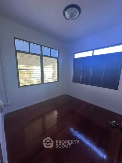 Spacious room with wooden flooring and large windows for natural light.