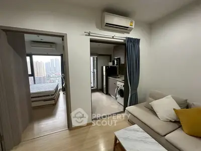 Modern apartment with open living area, bedroom, and kitchen featuring washing machine and microwave.