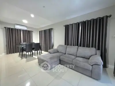 Spacious living room with modern gray sofa and dining area, perfect for family gatherings.