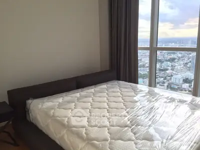 Spacious bedroom with stunning city view from large windows, featuring a comfortable bed and modern decor.
