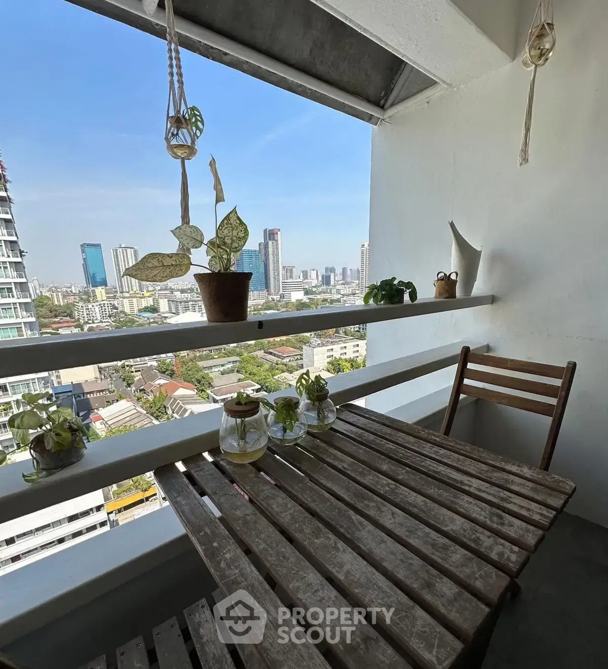 Charming balcony with city view, featuring rustic wooden table and plants, perfect for relaxation.