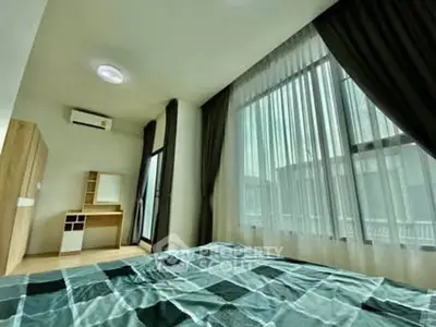 Spacious bedroom with large windows and modern furnishings in a stylish apartment.