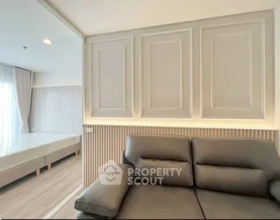 Modern living room with elegant paneling and cozy sofa, adjacent to a bright bedroom.