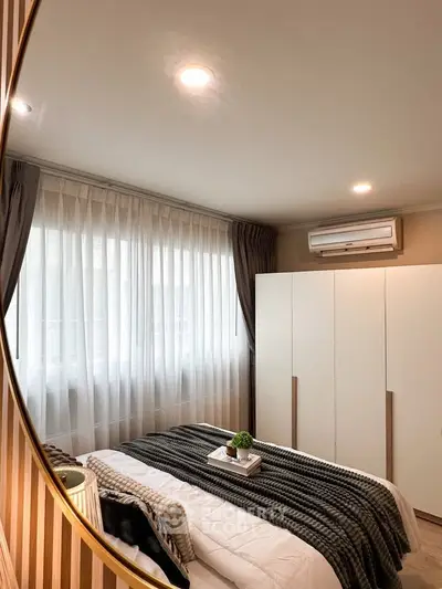 Cozy bedroom with modern decor and natural light, featuring a stylish air conditioning unit and elegant curtains.