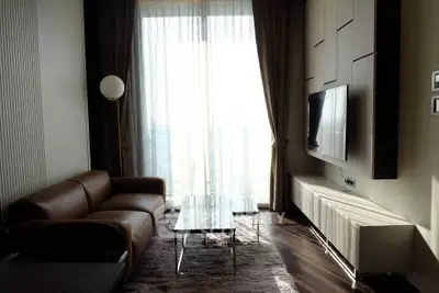 Modern living room with sleek furniture and large window offering natural light.