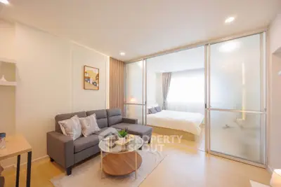 Modern open-plan living room with cozy bedroom separated by glass sliding doors, featuring stylish decor.