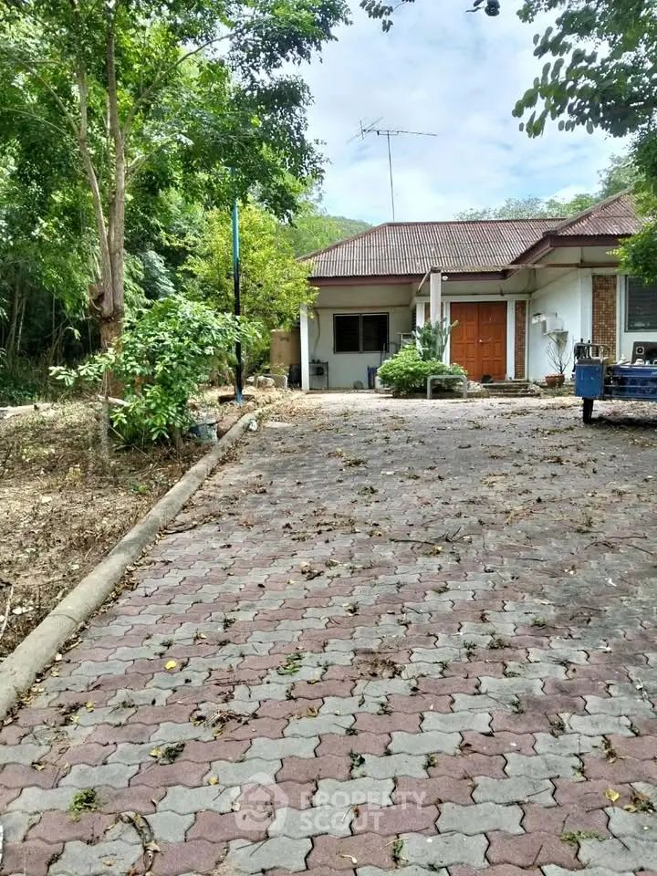Charming suburban home with spacious driveway and lush greenery.