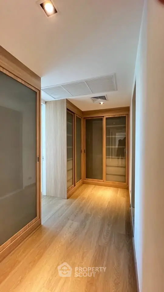 Spacious walk-in closet with wooden sliding doors and elegant lighting