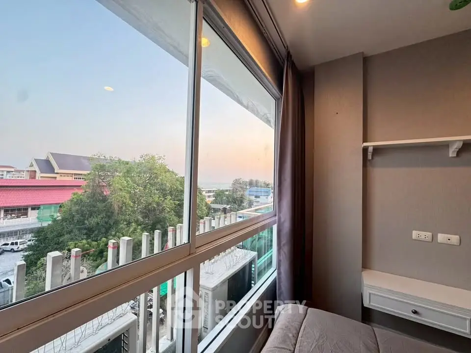 Cozy bedroom with large window offering a serene view of the cityscape and greenery.
