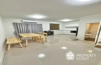 Spacious open-plan living area with gleaming tiled floors, modern kitchen appliances, and ample natural light, perfect for entertaining and comfortable living.