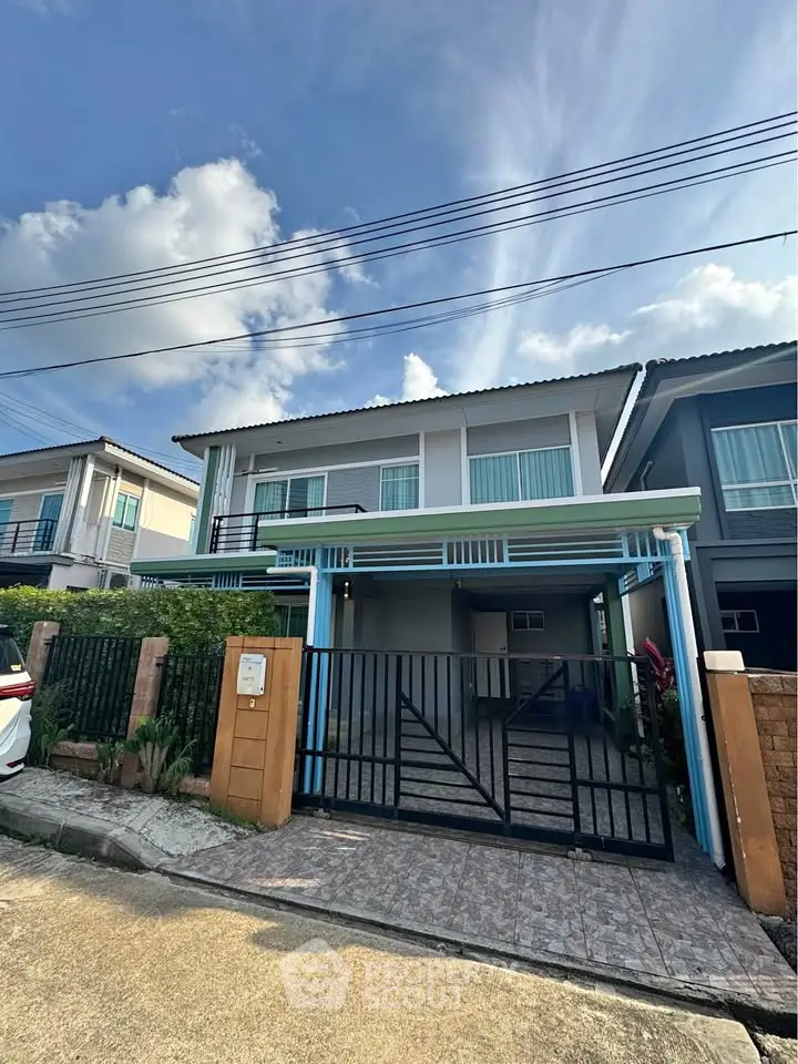 Modern two-story house with gated entrance and driveway in a suburban neighborhood.