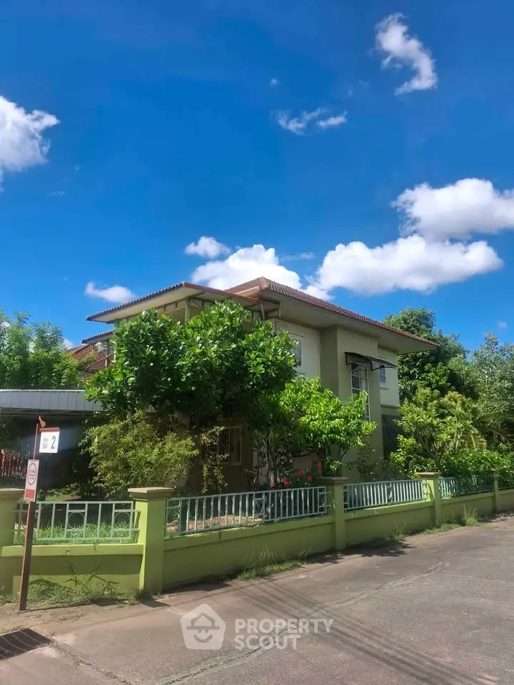 Charming two-story house with lush greenery and clear blue sky