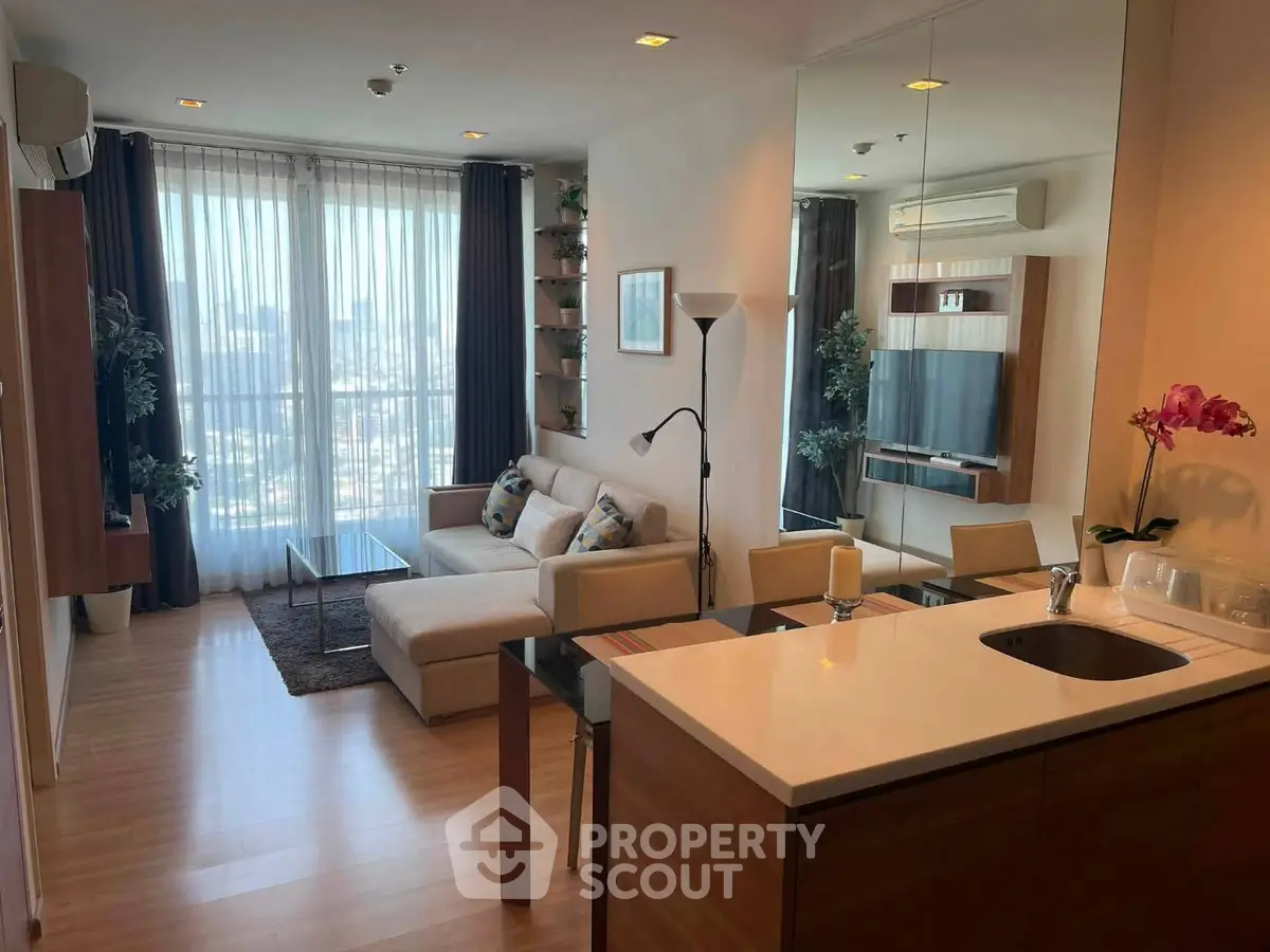 Modern living room with open kitchen, large windows, and city view.