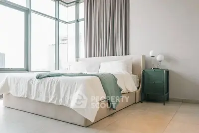 Spacious bedroom with large windows and modern decor in a luxury apartment.