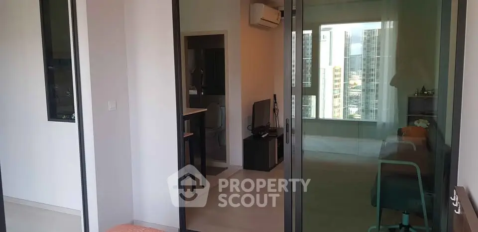 Modern apartment interior with glass doors and city view, featuring a cozy living area and sleek design.