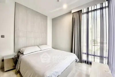 Modern bedroom with large window and neutral decor in a high-rise apartment.