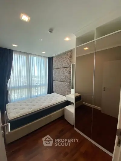 Modern bedroom with large window, mirrored wardrobe, and stylish decor in a high-rise apartment.