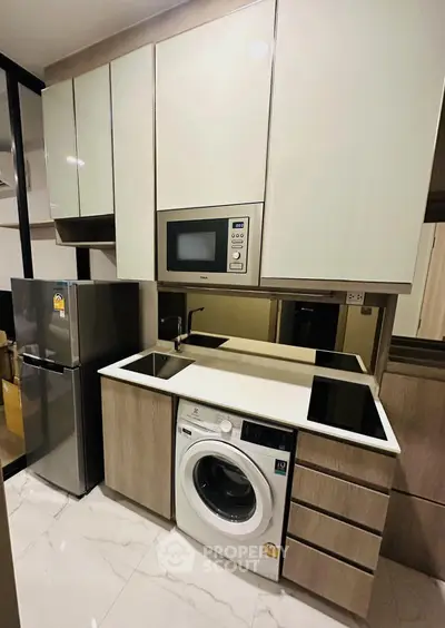 Modern kitchen with sleek appliances, integrated washing machine, and microwave in stylish cabinetry.