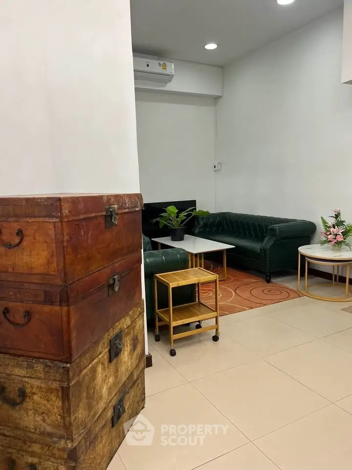 Charming living room with elegant green sofas and vintage wooden trunks, perfect for cozy gatherings.
