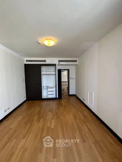 Spacious empty room with wooden flooring and built-in wardrobe, ideal for customization.