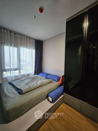 Cozy bedroom with large window and modern wardrobe in stylish apartment