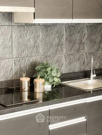Modern kitchen with sleek cabinetry and elegant countertop, featuring a stylish sink and decorative elements.