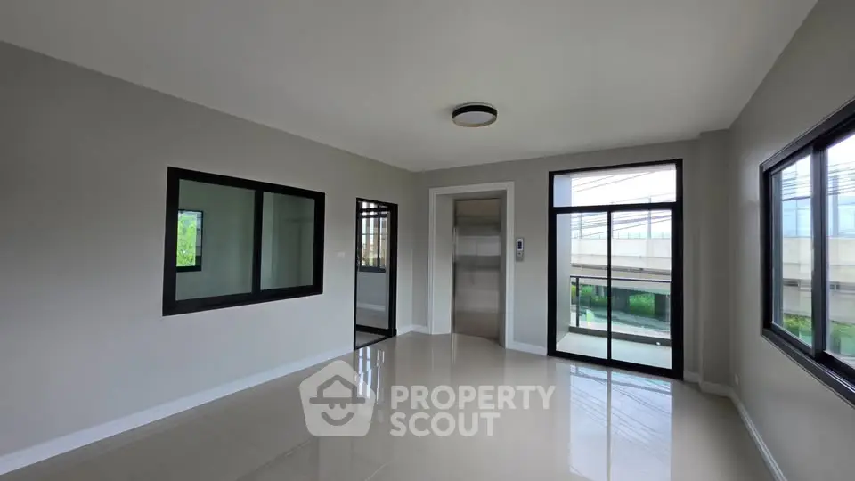 Spacious modern living room with large windows and sleek elevator access.