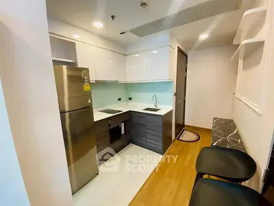 Modern compact kitchen with sleek cabinets and stainless steel appliances in a cozy apartment.