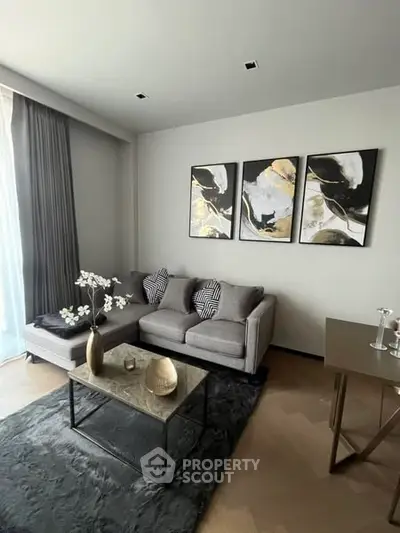 Modern living room with stylish decor and abstract art, featuring a cozy gray sofa and elegant coffee table.