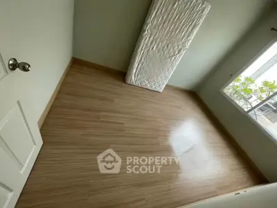 Spacious empty room with wooden flooring and large window view