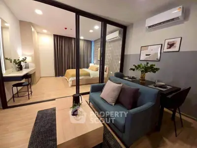 Modern studio apartment with stylish living area and cozy bedroom separated by glass partition.