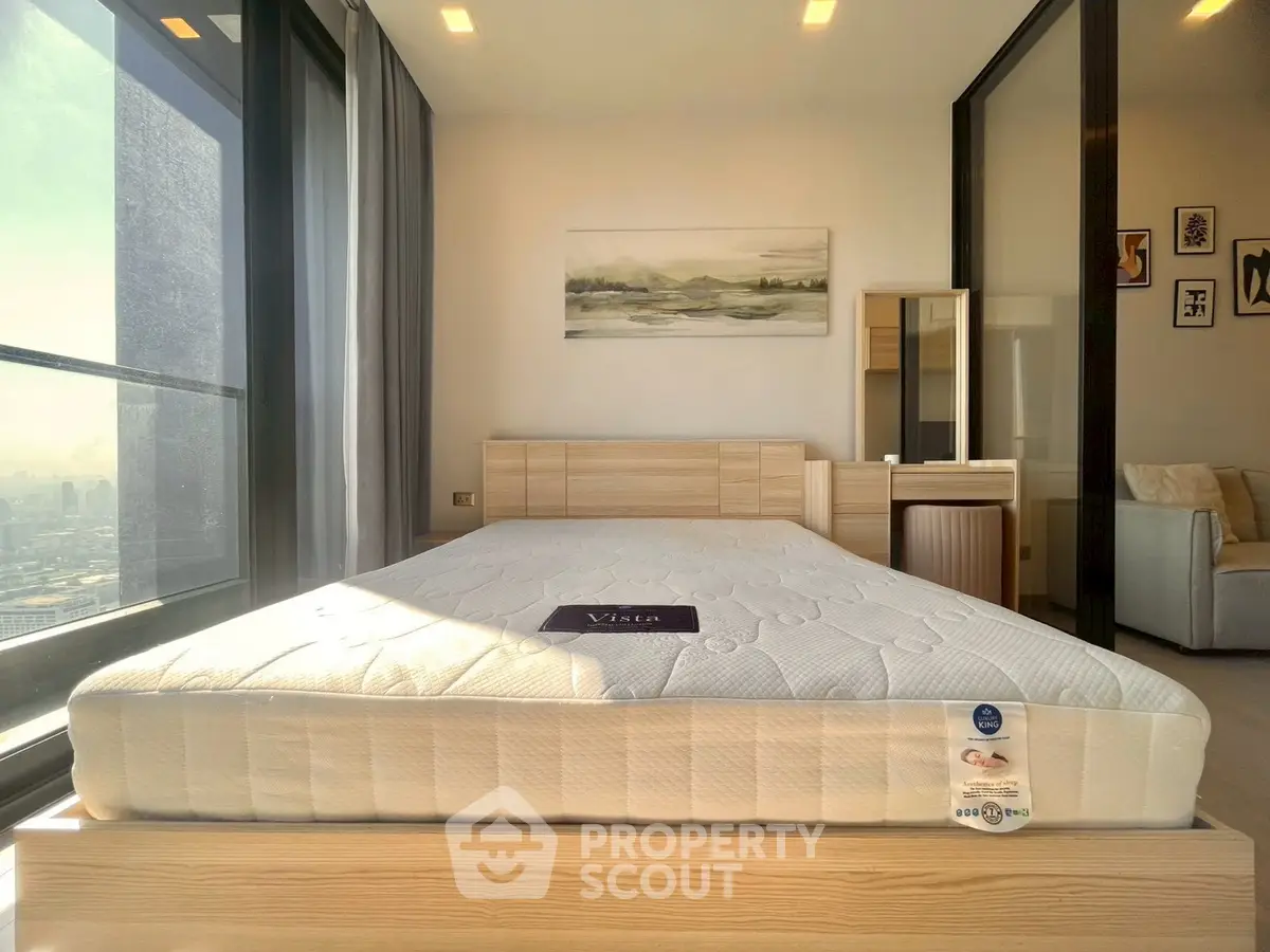 Spacious bedroom with large window offering stunning city views, modern furniture, and elegant decor.