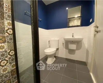Modern bathroom with stylish blue and white tiles, featuring a sleek sink and toilet.