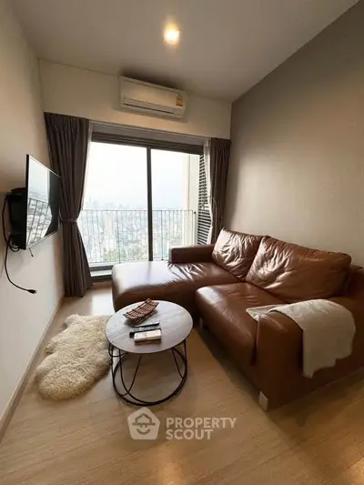 Cozy living room with leather sofa and city view from large window.