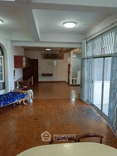 Spacious living room with parquet flooring and sliding glass doors leading to balcony.